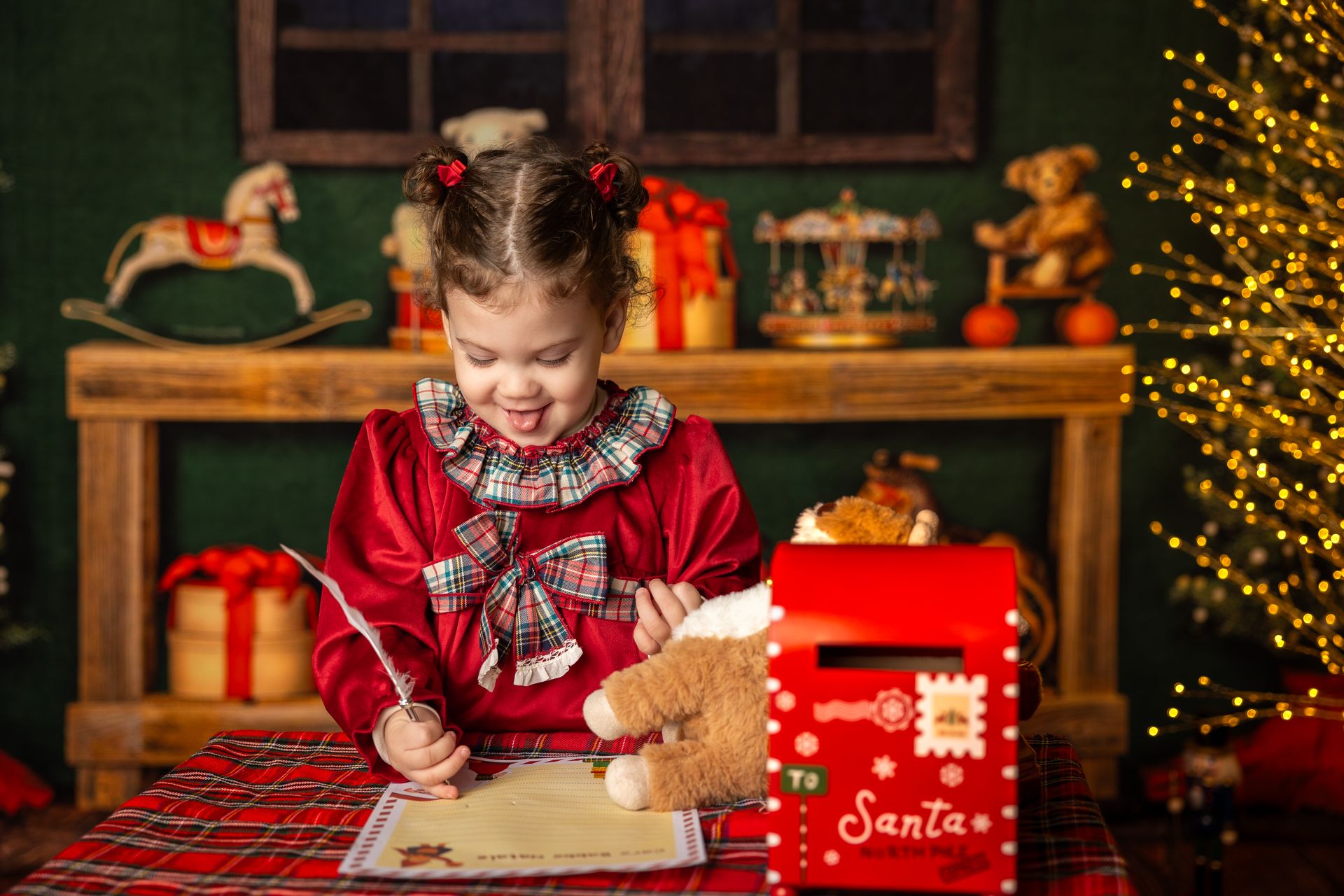 Bimba con i codini scrive la letterina accanto all'orsetto e alla cassetta rossa delle lettere