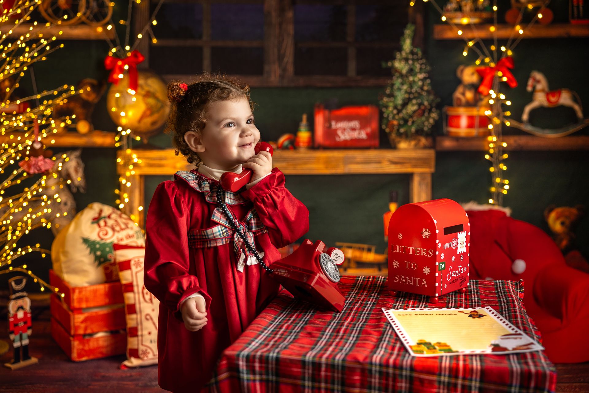Bimba in abito rosso al tavolo apparecchiato con la letterina e la cassetta delle lettere per Babbo Natale